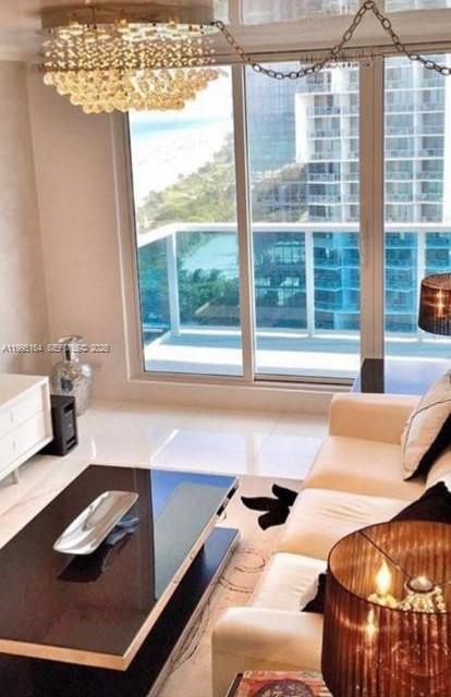 A modern living room features a crystal chandelier, a dark coffee table, and balcony views — 2301 Collins Ave # 1507, Miami Beach FL 33139, MIAMI BEACH, FL