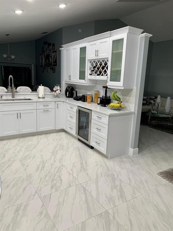 A kitchen features white cabinetry, a wine rack, a beverage cooler, and marble-patterned tile flooring — 2062 SUE ELLEN COURT, APOPKA, FL