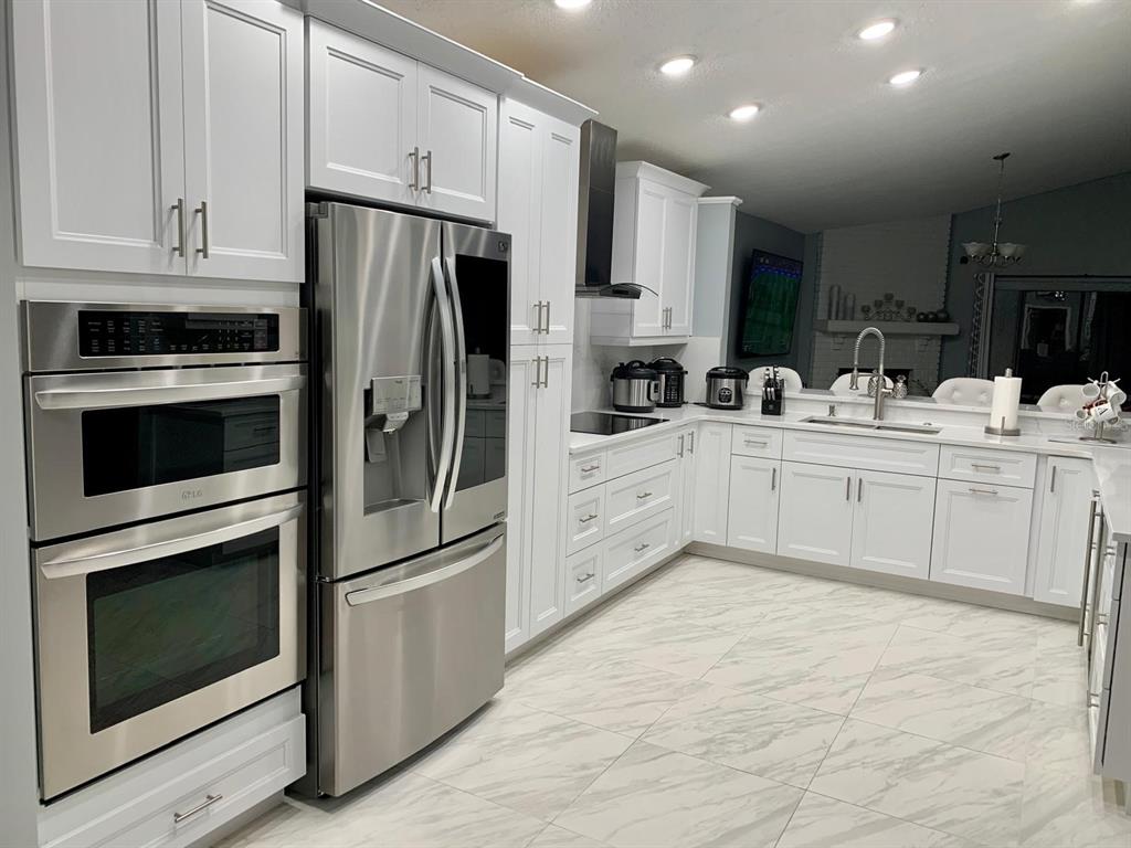 A modern kitchen features white cabinets, stainless steel appliances, and light-colored marble-patterned tile flooring — 2062 SUE ELLEN COURT, APOPKA, FL