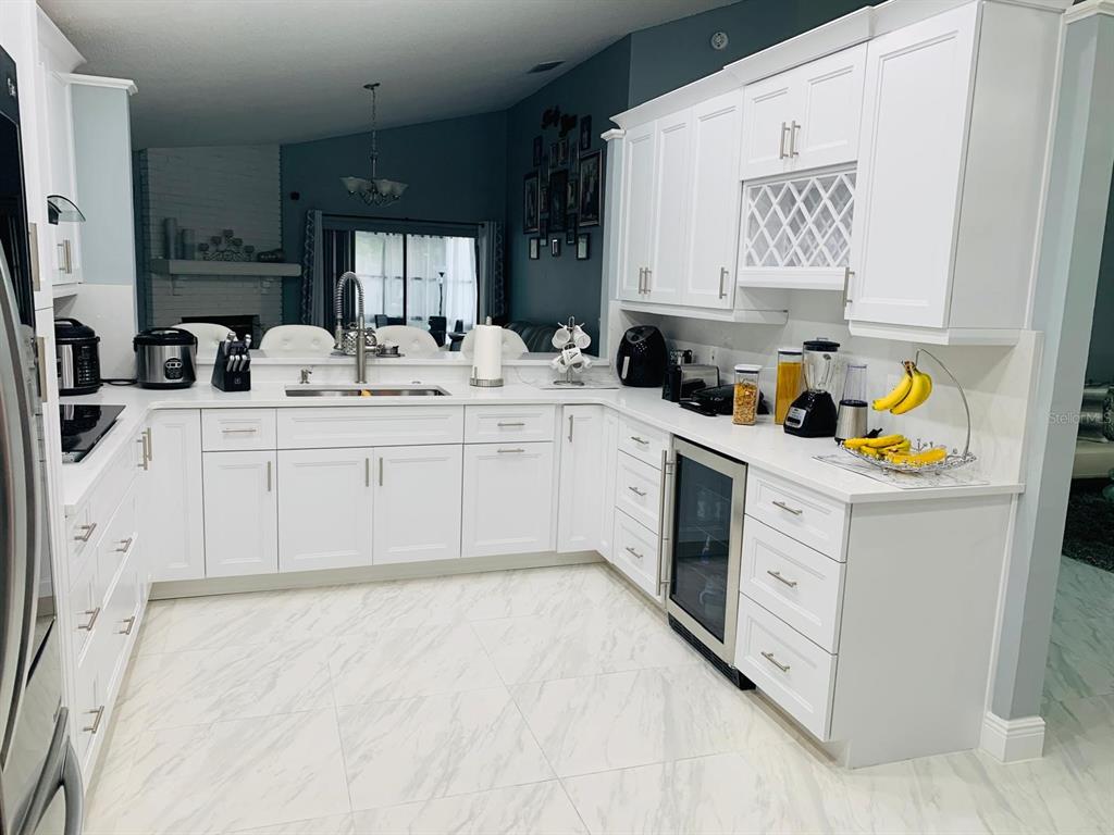 A white kitchen features marble-look tile floors, white cabinetry, and a wine refrigerator — 2062 SUE ELLEN COURT, APOPKA, FL