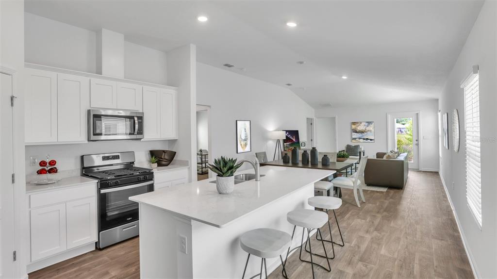 A modern kitchen with white cabinets, a quartz island, and stainless steel appliances — 5 DIVOT PLACE, BUNNELL, FL