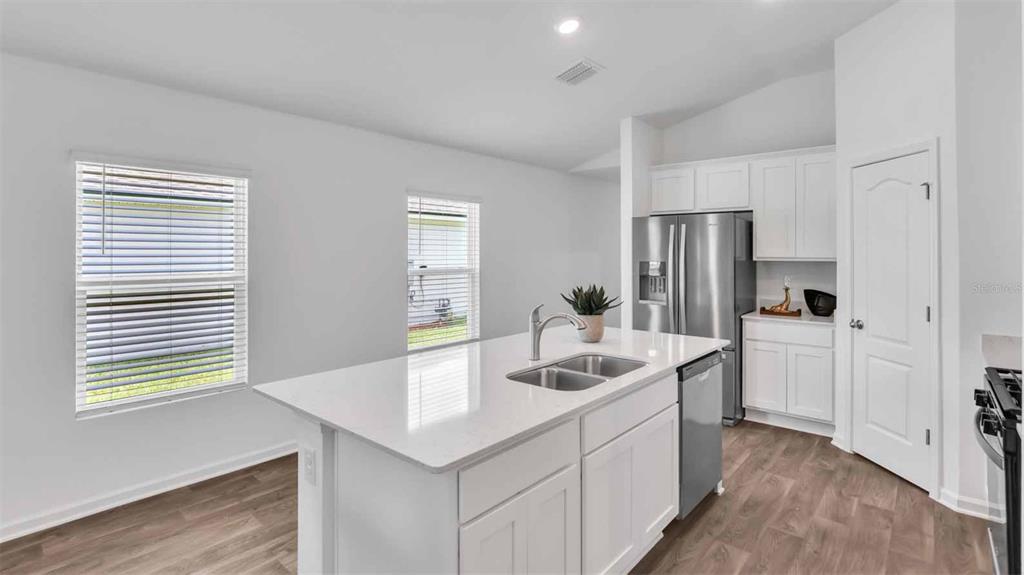 A kitchen with a white island, stainless steel appliances, and white cabinets on wood flooring — 5 DIVOT PLACE, BUNNELL, FL