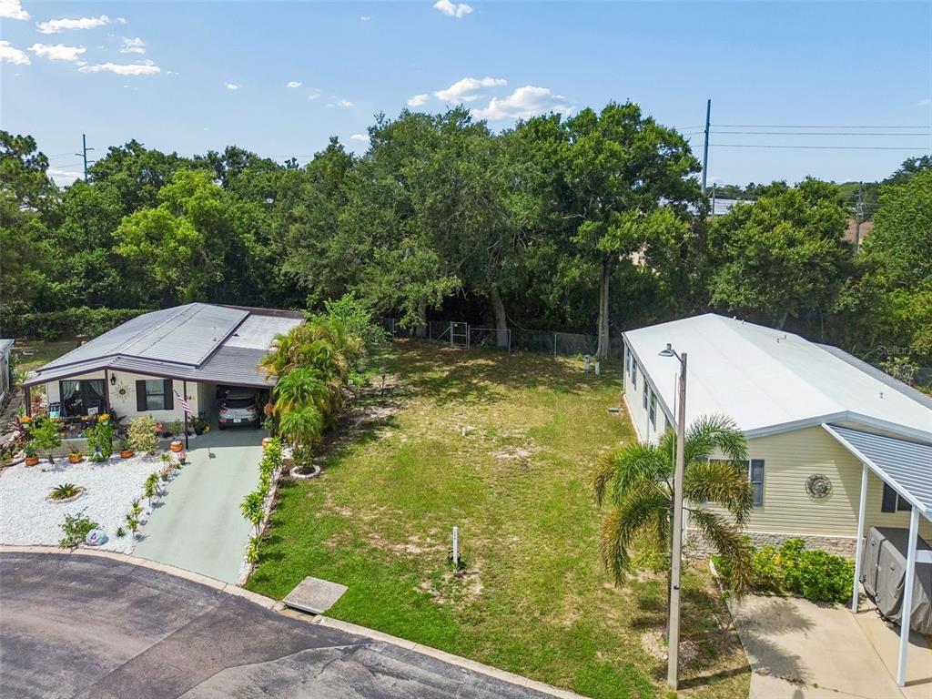 An aerial view shows a vacant grassy lot situated between two single-story residential homes — 9790 66TH STREET UNIT 368, PINELLAS PARK, FL
