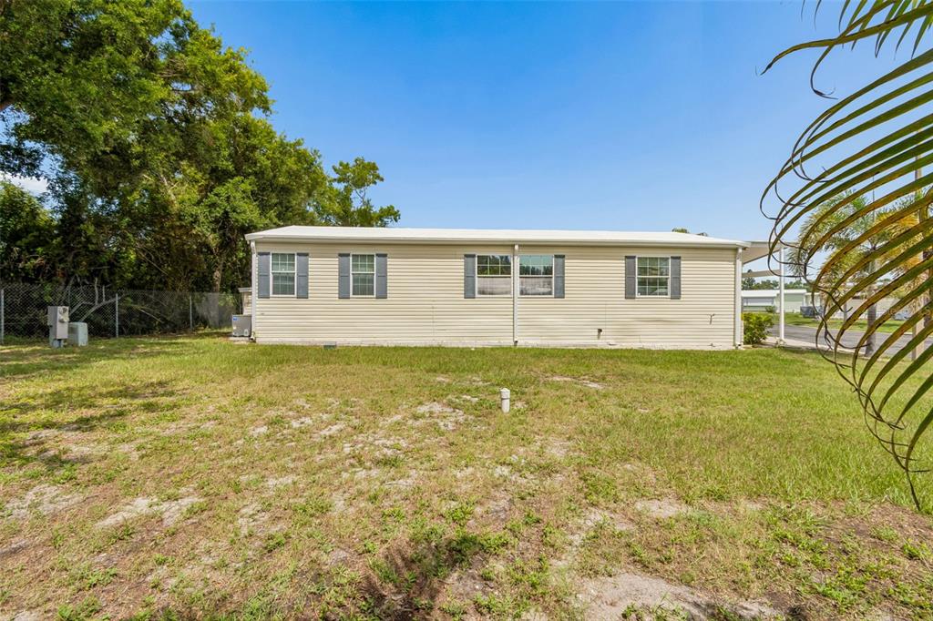 The exterior of a single-story manufactured home features light-colored siding and a grassy yard — 9790 66TH STREET UNIT 368, PINELLAS PARK, FL