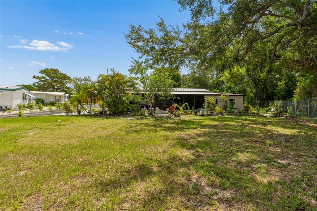 A single-story house with a screened porch sits behind a large, grassy yard — 9790 66TH STREET UNIT 368, PINELLAS PARK, FL