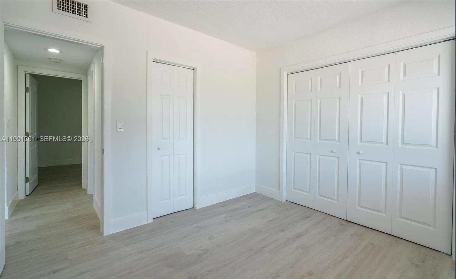 An interior view shows a room with light wood-look flooring and a doorway to another space — 1248 Marseille Dr # 2, Miami Beach FL 33141, MIAMI BEACH, FL