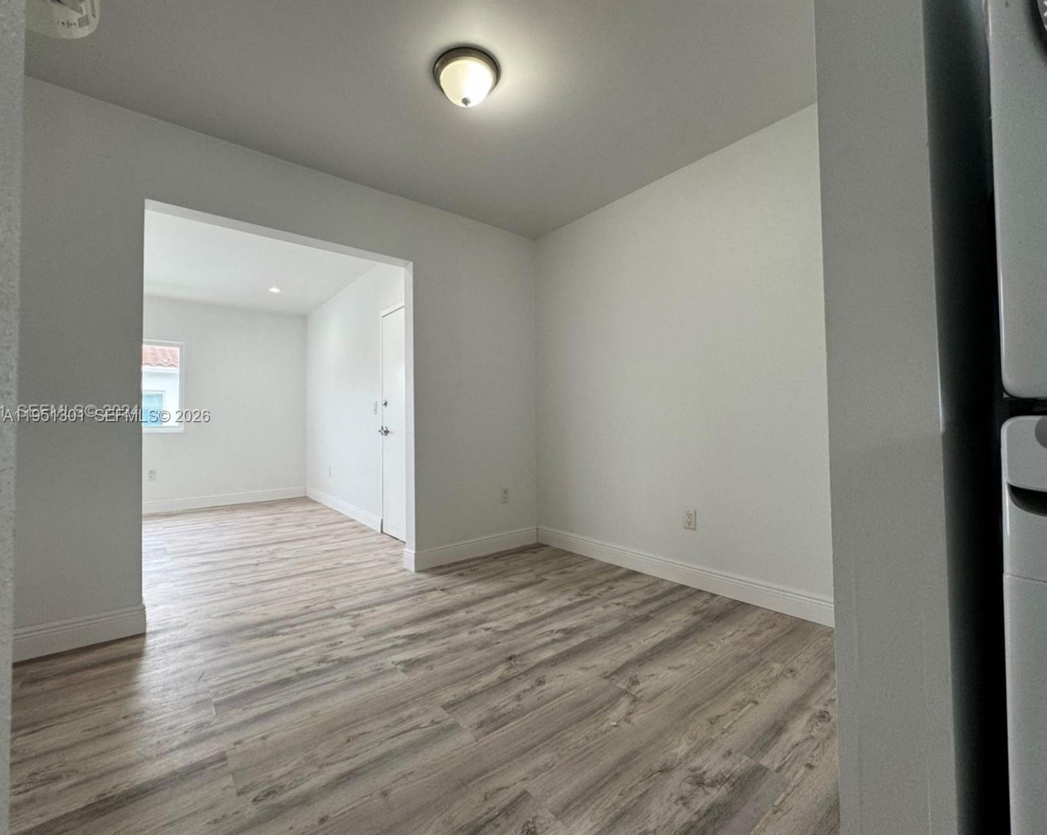 An empty room with light gray walls, wood-look flooring, and corner windows — 1248 Marseille Dr # 2, Miami Beach FL 33141, MIAMI BEACH, FL