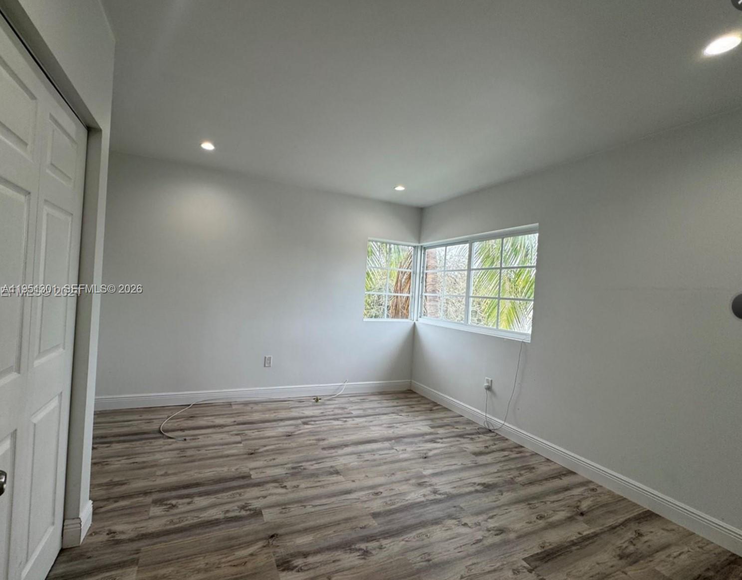 An empty bedroom features light gray walls, wood-look flooring, recessed lighting, and a single window — 1248 Marseille Dr # 2, Miami Beach FL 33141, MIAMI BEACH, FL