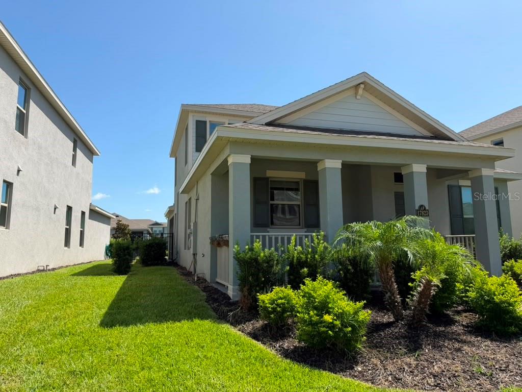 A two-story house features a front porch, a grassy side yard, and landscaping — 17823 ADRIFT ROAD, WINTER GARDEN, FL
