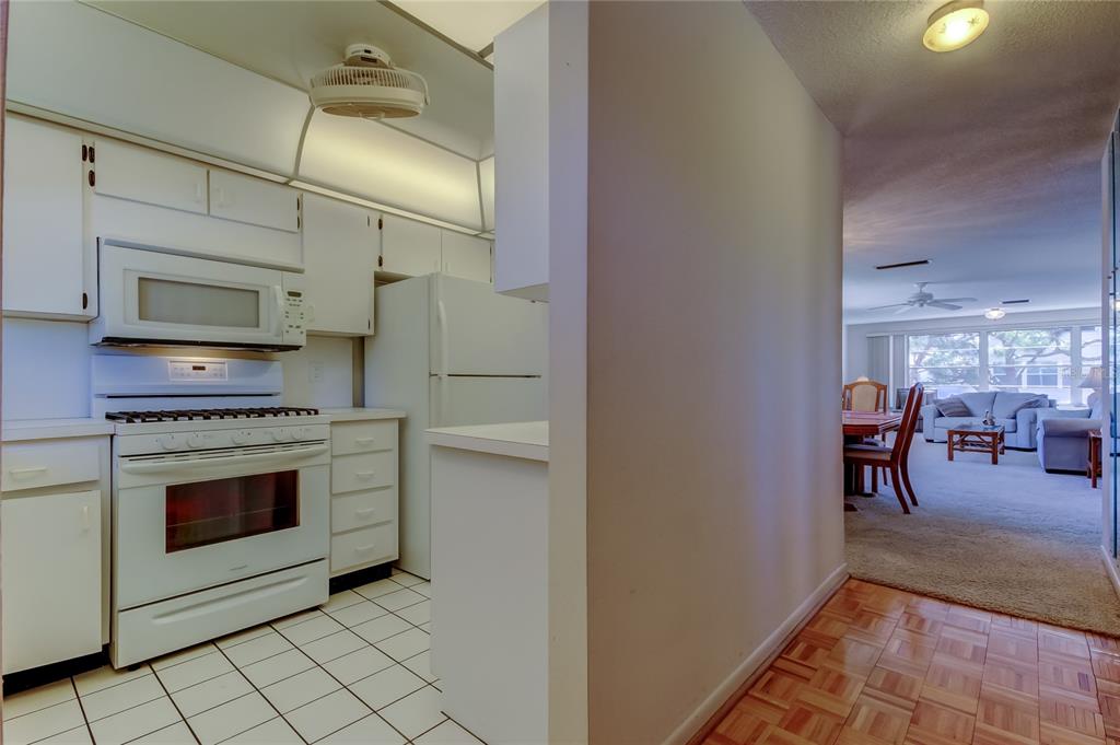 A white kitchen with tile floors opens into a carpeted dining and living area — 5521 80TH STREET N UNIT 315, ST PETERSBURG, FL