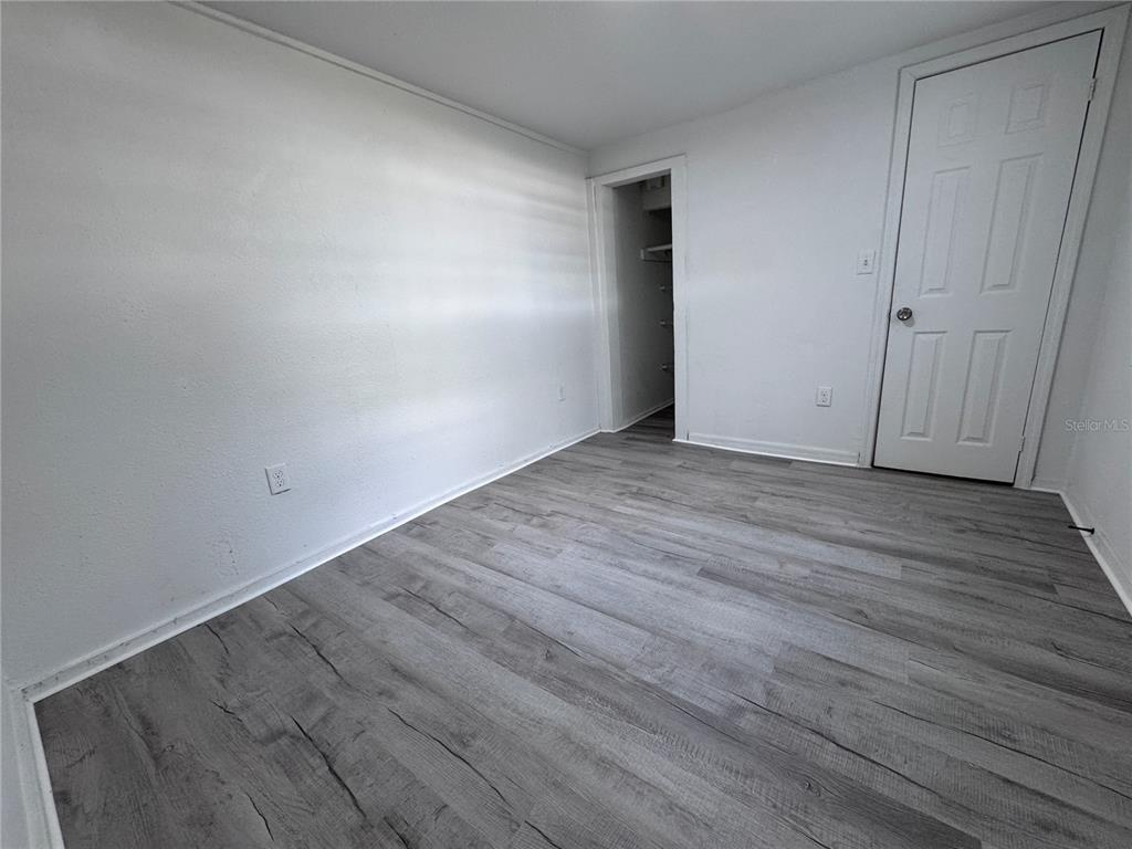 An empty bedroom with white walls, gray wood-look flooring, and a closet doorway — 58 MILEHAM DRIVE, ORLANDO, FL