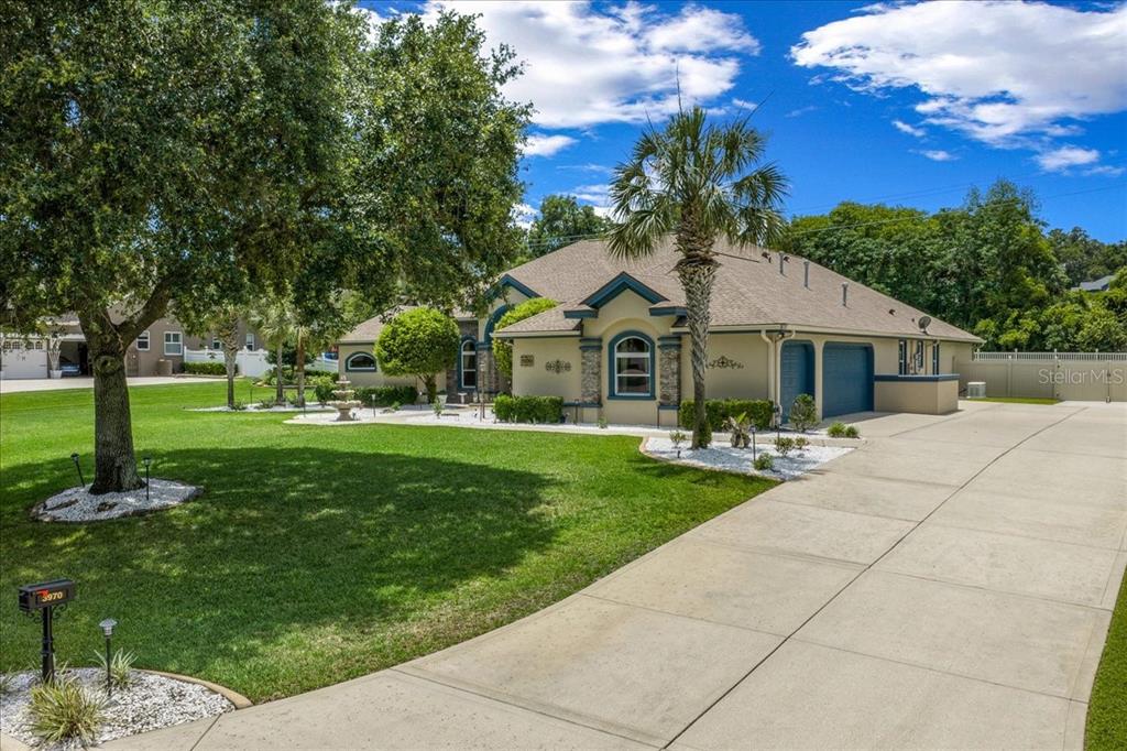 A single-story house with a large lawn, a central fountain, and palm trees — 3970 SE 39TH CIRCLE, OCALA, FL