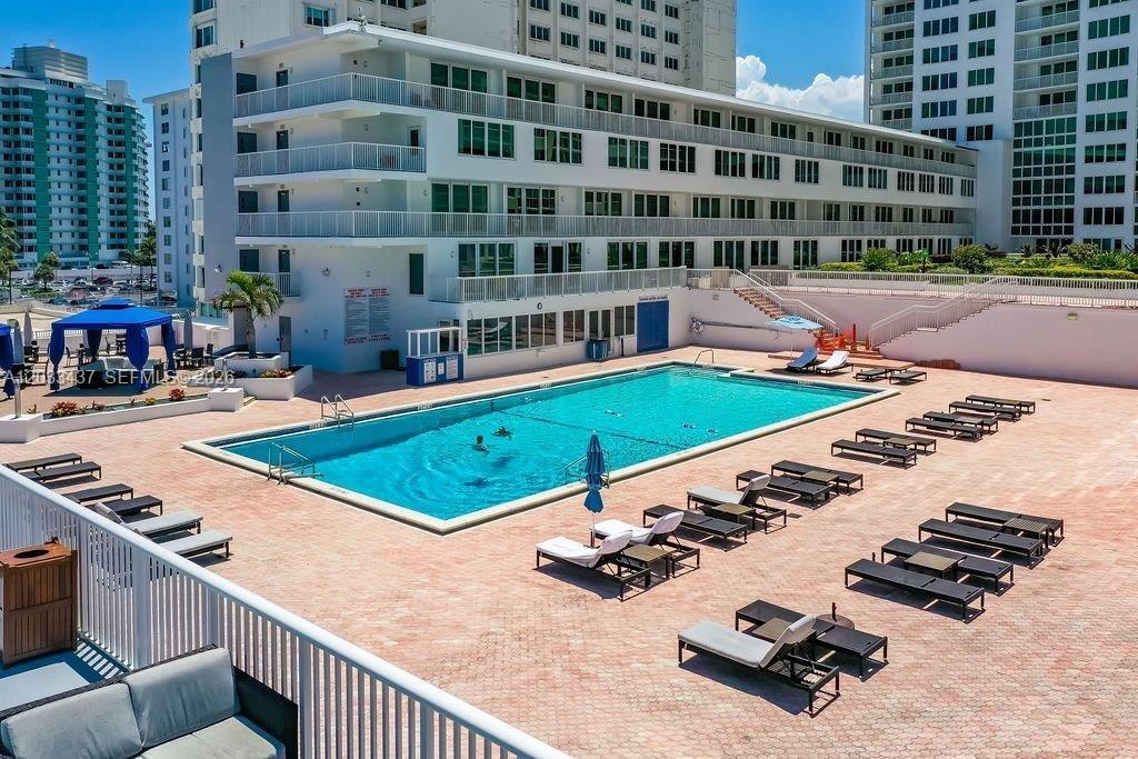 An outdoor swimming pool surrounded by lounge chairs on a paved deck at a resort — 5401 Collins Ave # 513, Miami Beach FL 33140, MIAMI BEACH, FL