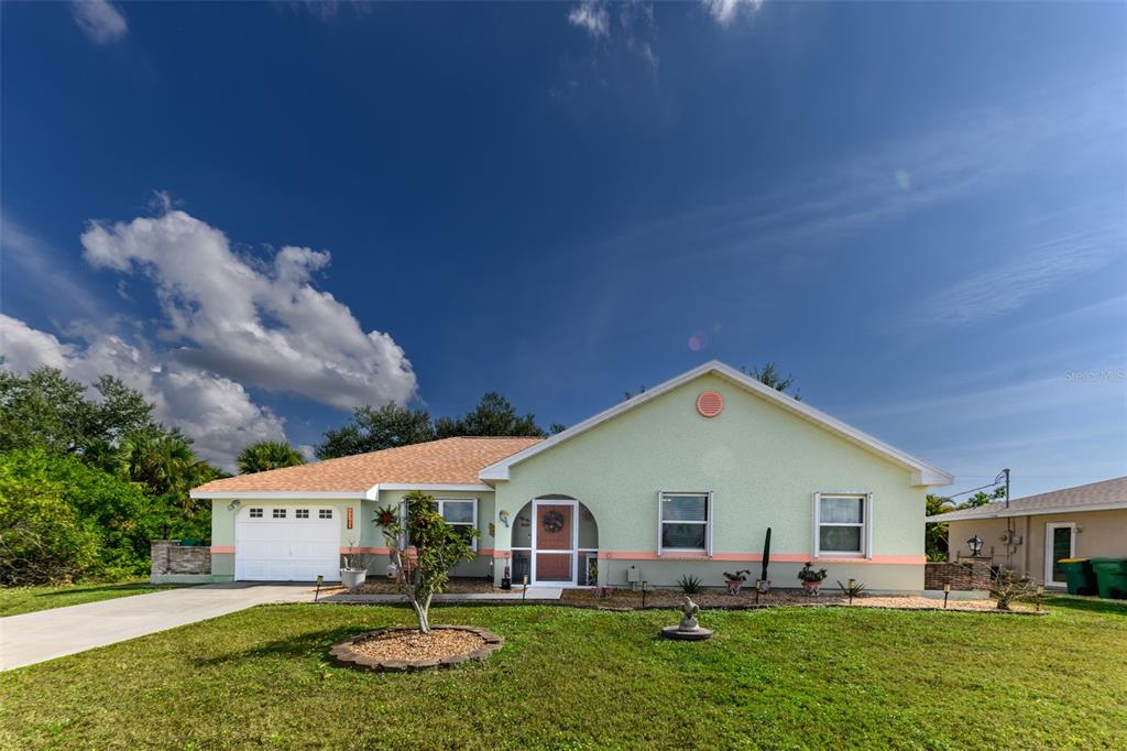 A single-story house with light green stucco walls, a white garage door, and a lawn — 4360 FLAMINGO BOULEVARD, PORT CHARLOTTE, FL