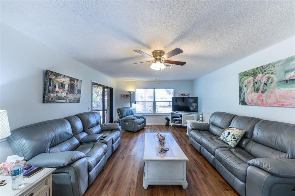 A living room features two gray leather sofas, a coffee table, and a ceiling fan — 4360 FLAMINGO BOULEVARD, PORT CHARLOTTE, FL