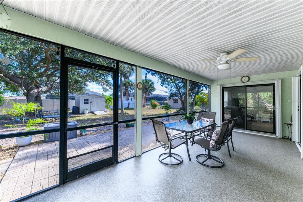 A screened-in patio features a dining set, a ceiling fan, and views of a backyard — 4360 FLAMINGO BOULEVARD, PORT CHARLOTTE, FL