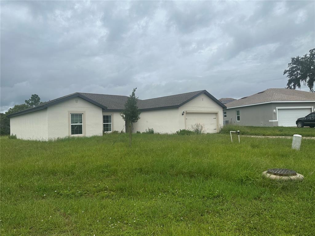 A single-story house with a white stucco exterior and a two-car garage — 521 BIG BLACK WAY, KISSIMMEE, FL