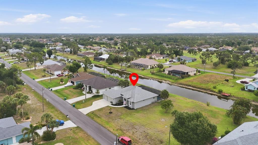 An aerial view of a single-story house with a gray roof situated along a canal — 48 LONG MEADOW LANE, ROTONDA WEST, FL
