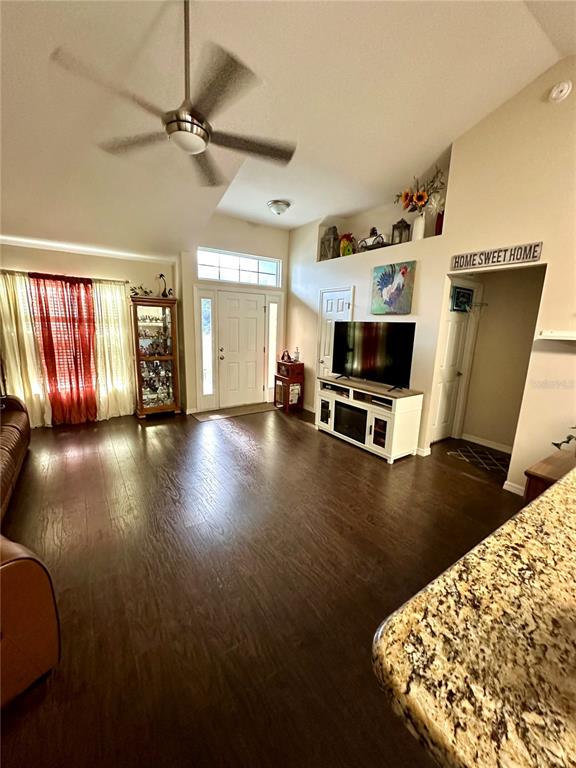 A living room features dark wood floors, a ceiling fan, and a television on a console — 40320 W 2ND AVENUE, UMATILLA, FL