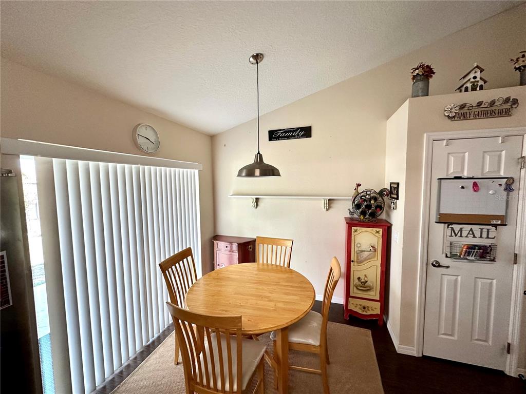 A dining area features a round wooden table, four chairs, a pendant light, and a door — 40320 W 2ND AVENUE, UMATILLA, FL
