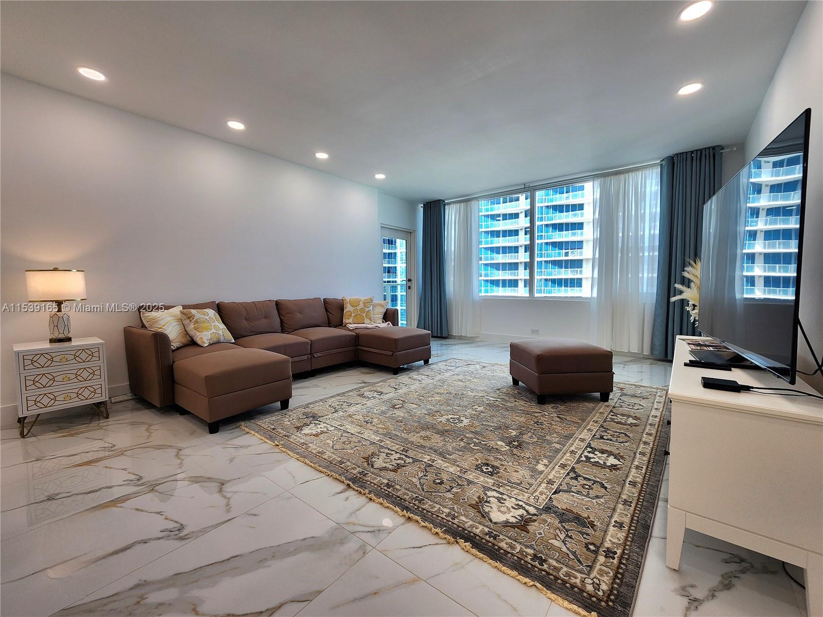 A living room features a brown sectional sofa, a patterned area rug, and marble flooring — 3505 S Ocean Dr # 1509, Hollywood FL 33019, HOLLYWOOD, FL