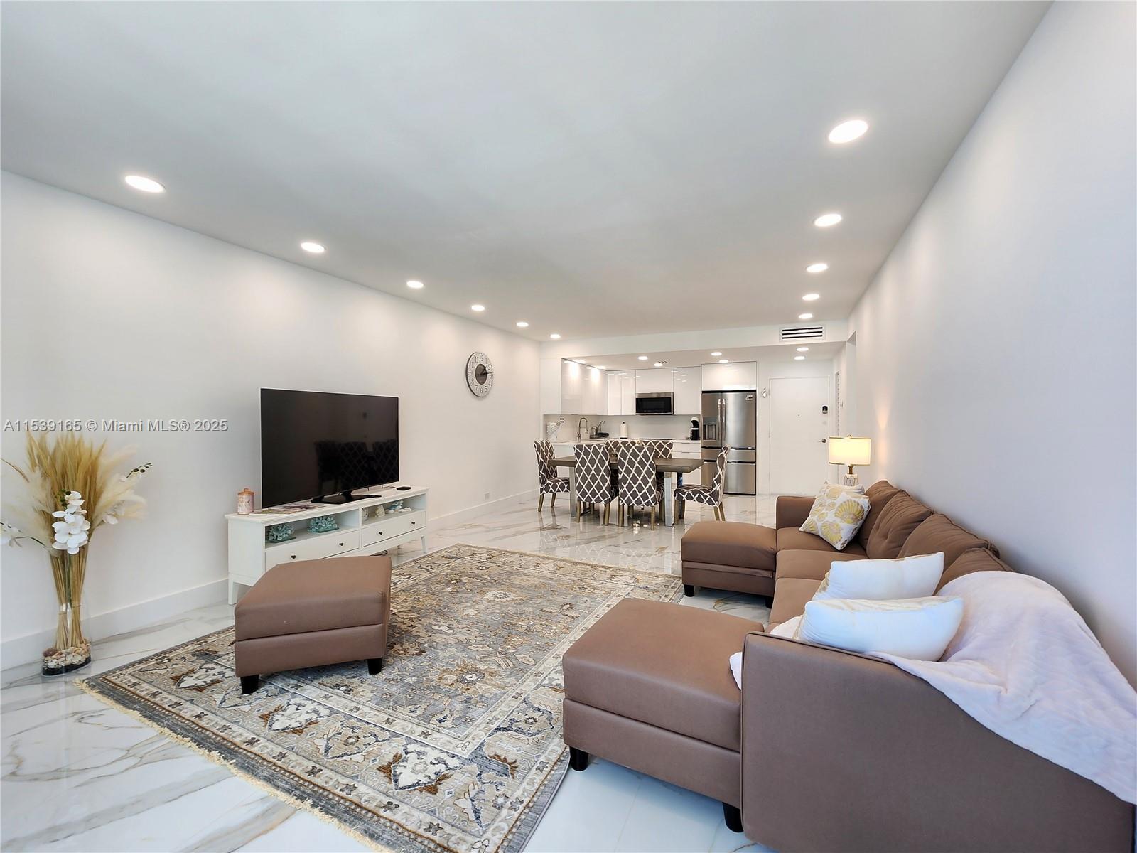 A living room and dining area feature white walls, marble floors, and brown sectional furniture — 3505 S Ocean Dr # 1509, Hollywood FL 33019, HOLLYWOOD, FL