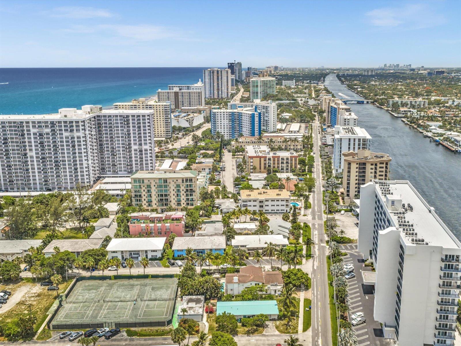 An aerial view shows high-rise buildings, a tennis court, and a waterway along the coast — 524 N Riverside Drive, Pompano Beach FL 33062, POMPANO BEACH, FL