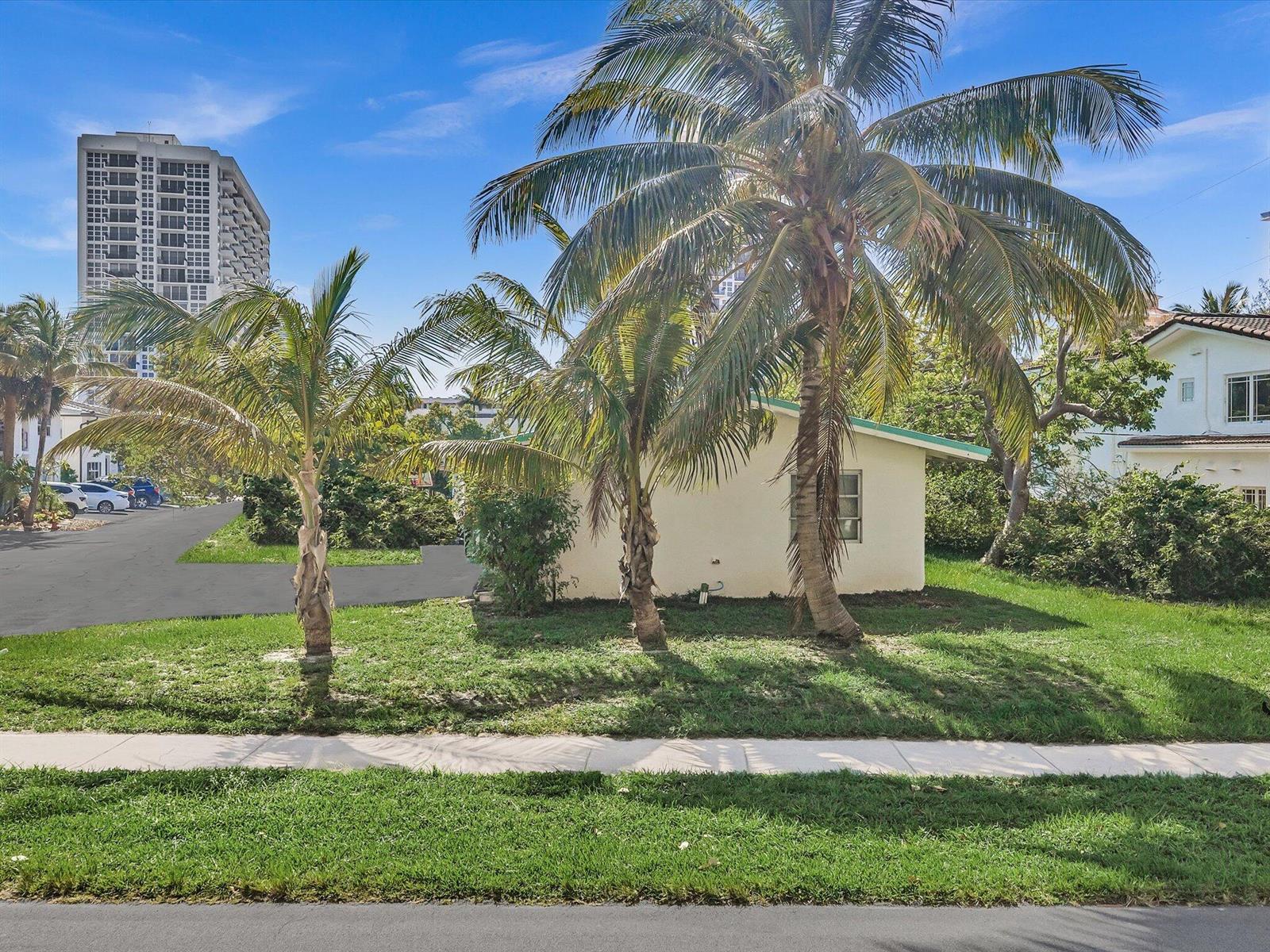 A small, light-colored house sits on a grassy lot with several palm trees — 524 N Riverside Drive, Pompano Beach FL 33062, POMPANO BEACH, FL