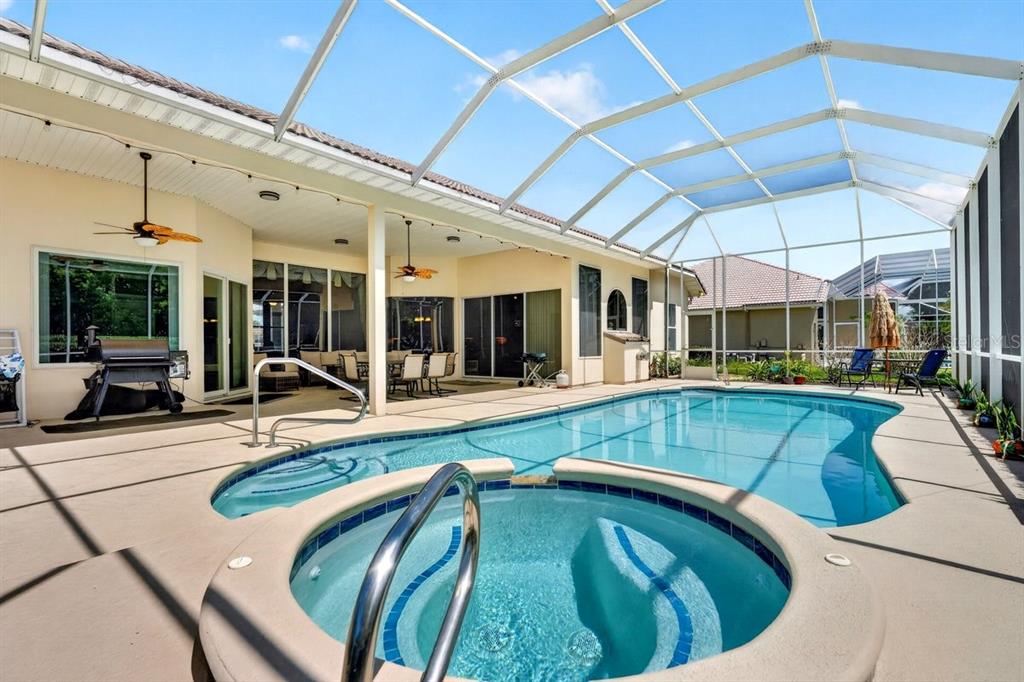 A screened-in patio features a swimming pool, a raised hot tub, and a covered seating area — 725 SEA DUCK DRIVE, DAYTONA BEACH, FL