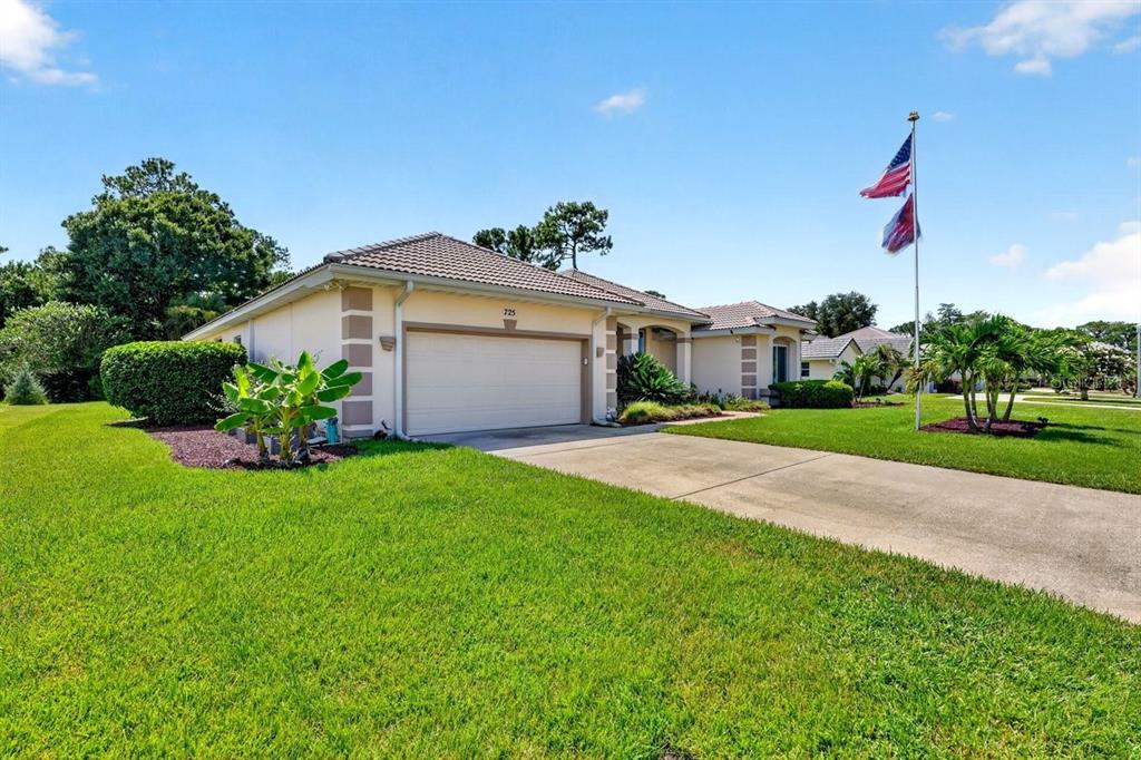 A single-story house with a beige stucco exterior, a two-car garage, and a flag pole — 725 SEA DUCK DRIVE, DAYTONA BEACH, FL