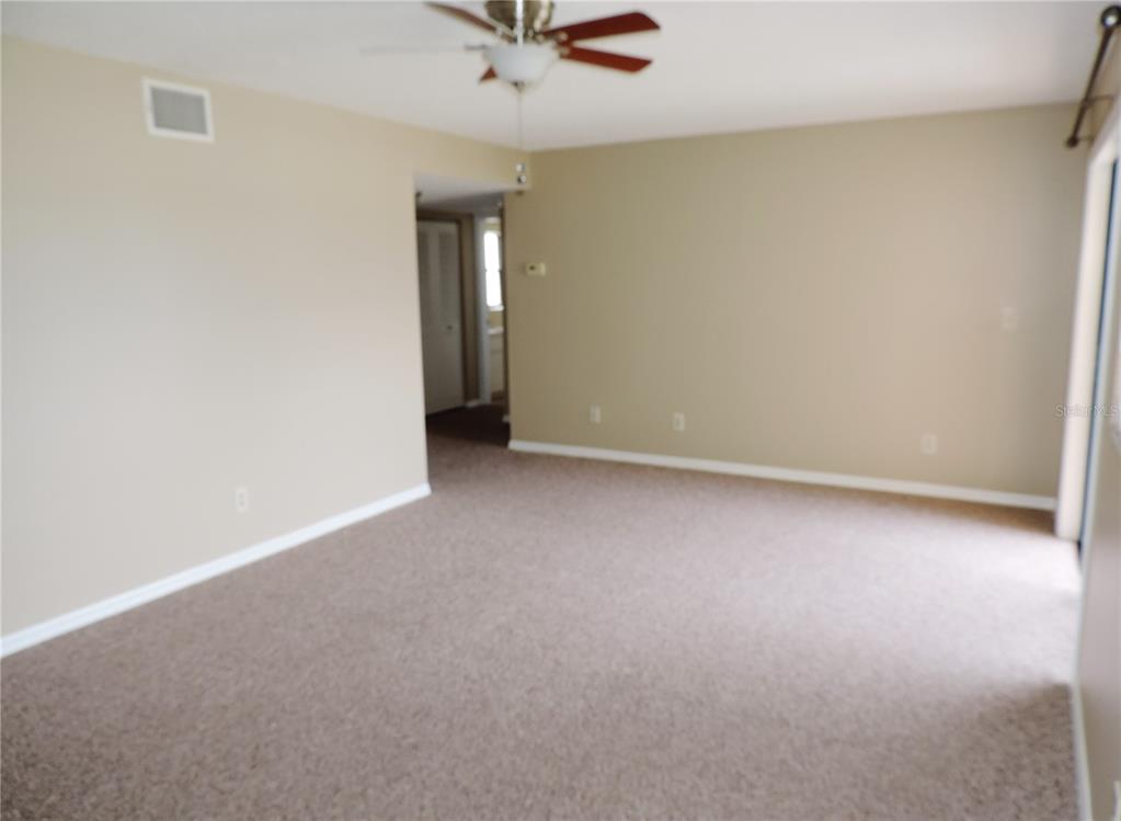 An empty room with beige walls, tan carpeting, and a ceiling fan — 145 116TH AVENUE UNIT 301, TREASURE ISLAND, FL