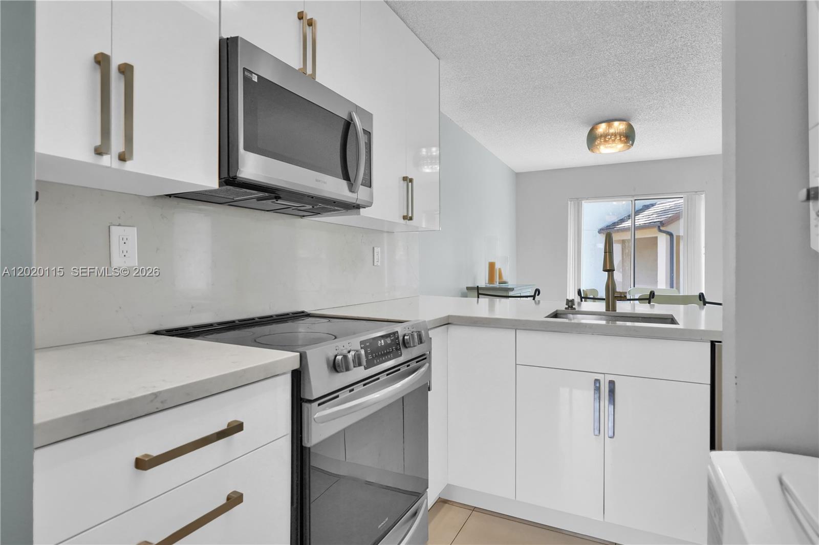 A modern kitchen features white cabinets, stainless steel appliances, and light-colored countertops — 13946 SW 91st Ter # 13946, Miami FL 33186, MIAMI, FL