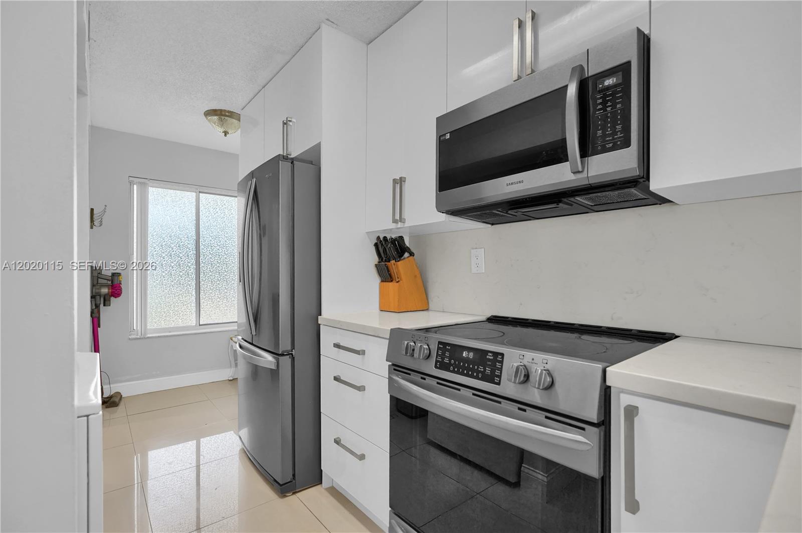 A kitchen features white cabinets, stainless steel appliances, and a window with blinds — 13946 SW 91st Ter # 13946, Miami FL 33186, MIAMI, FL