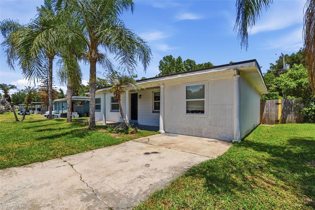 A white single-story house with a concrete driveway and palm trees in the front yard — 213 HAYS DRIVE, SANFORD, FL