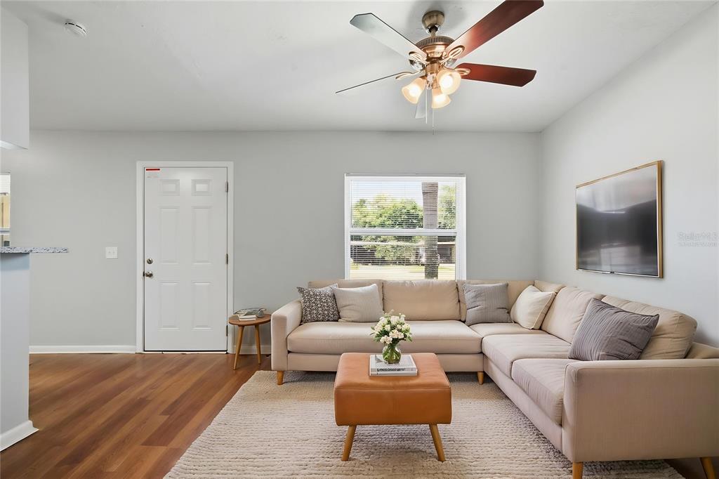 A living room features a beige sectional sofa, a leather ottoman, and a ceiling fan — 213 HAYS DRIVE, SANFORD, FL