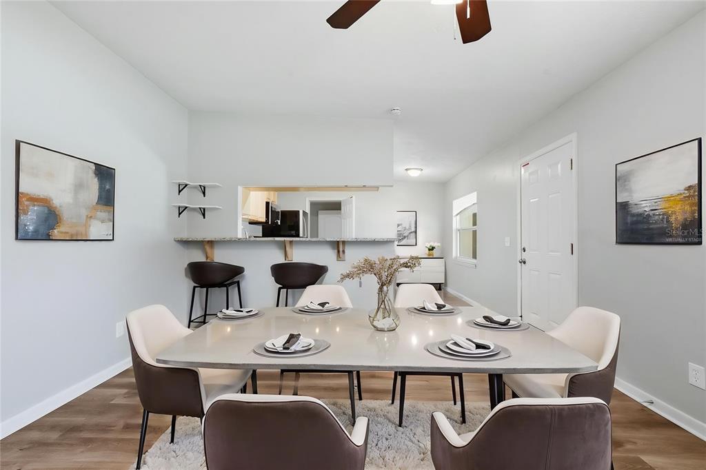 A dining room features a large table with six chairs, a breakfast bar, and artwork — 213 HAYS DRIVE, SANFORD, FL