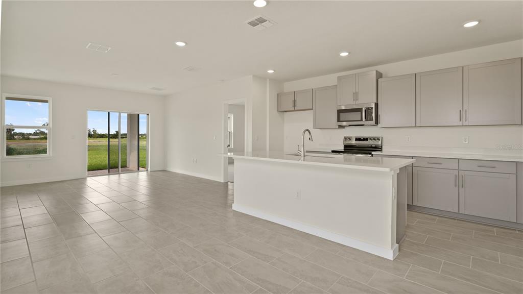A modern kitchen with light gray cabinets and a white island opens to a living area — 816 ANDREW STREET, WINTER HAVEN, FL