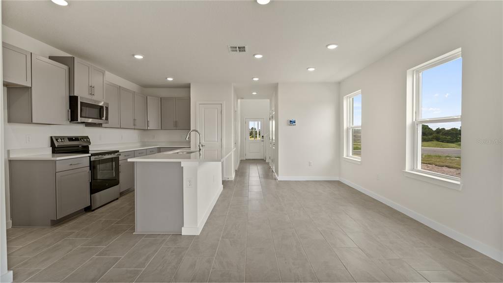 A modern kitchen features gray cabinets, white countertops, stainless steel appliances, and tile flooring — 816 ANDREW STREET, WINTER HAVEN, FL
