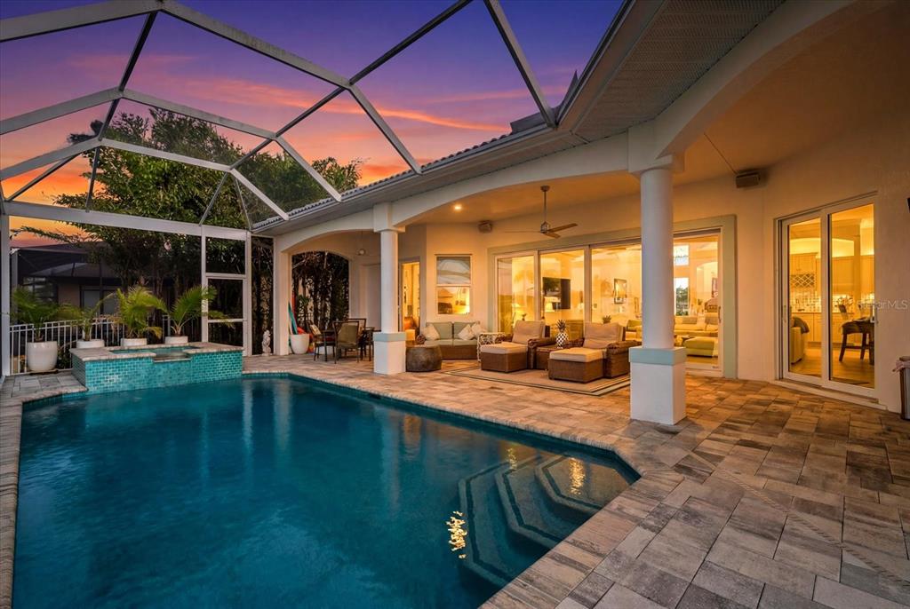 A screened-in patio features a swimming pool, spa, and outdoor seating area at sunset — 4227 NW 28TH STREET, CAPE CORAL, FL