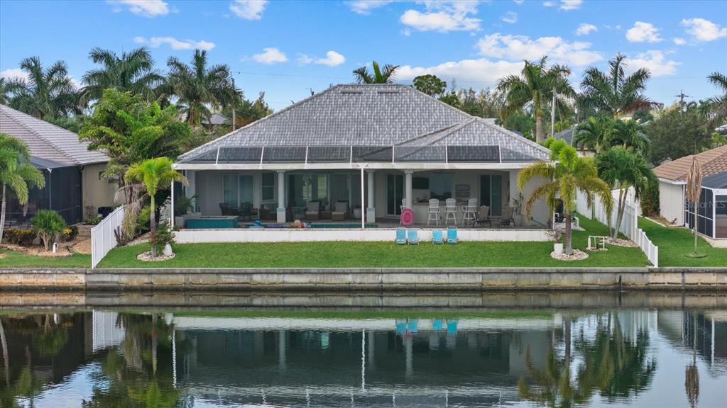 A waterfront house with a screened-in pool patio, palm trees, and a gray tiled roof — 4227 NW 28TH STREET, CAPE CORAL, FL