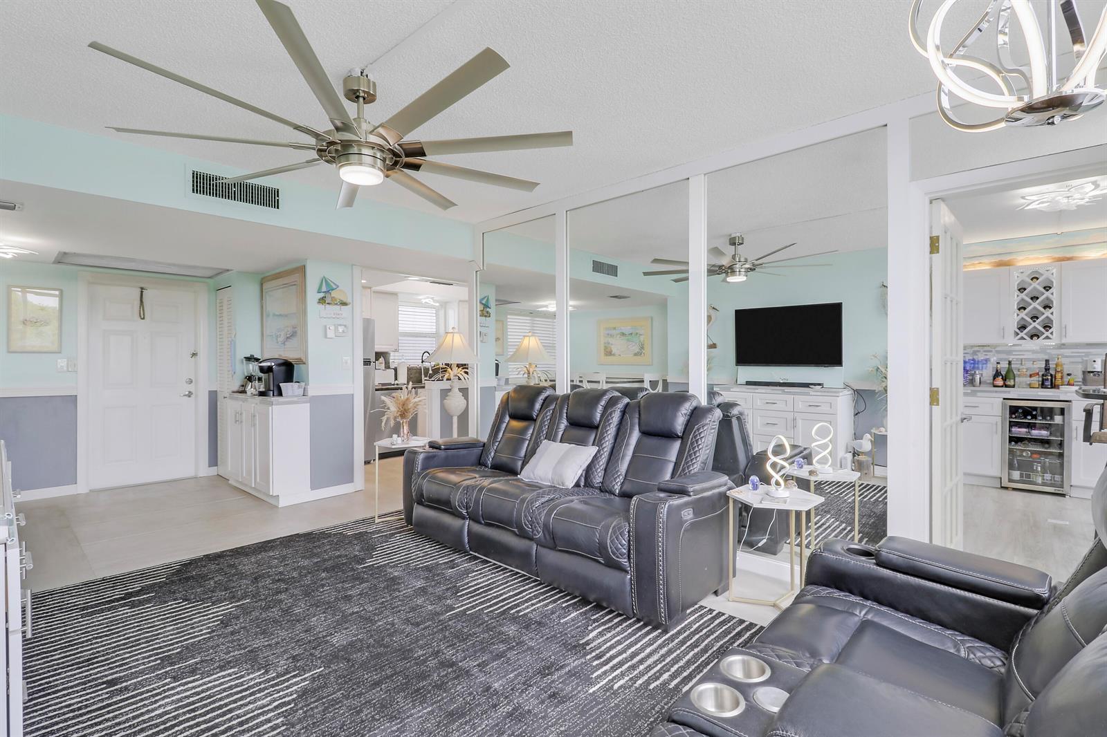 A living room features a dark leather sofa, a patterned rug, and mirrored wall panels — 1820 New Palm Way # 202, Boynton Beach FL 33435, BOYNTON BEACH, FL