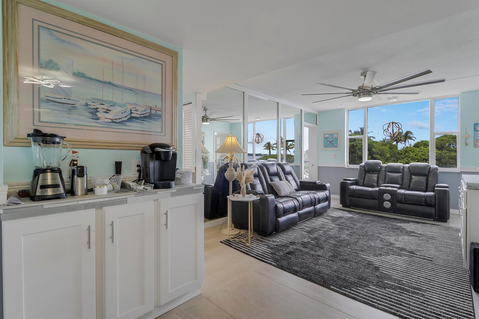A living room features a coffee station, dark leather sofas, and a large area rug — 1820 New Palm Way # 202, Boynton Beach FL 33435, BOYNTON BEACH, FL