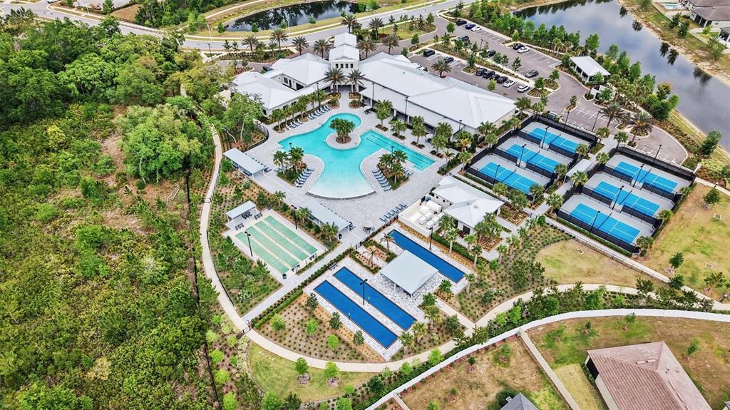 An aerial view shows a community clubhouse with a swimming pool, tennis courts, and landscaping — 10395 BANYAN BREEZE BOULEVARD, LAND O LAKES, FL