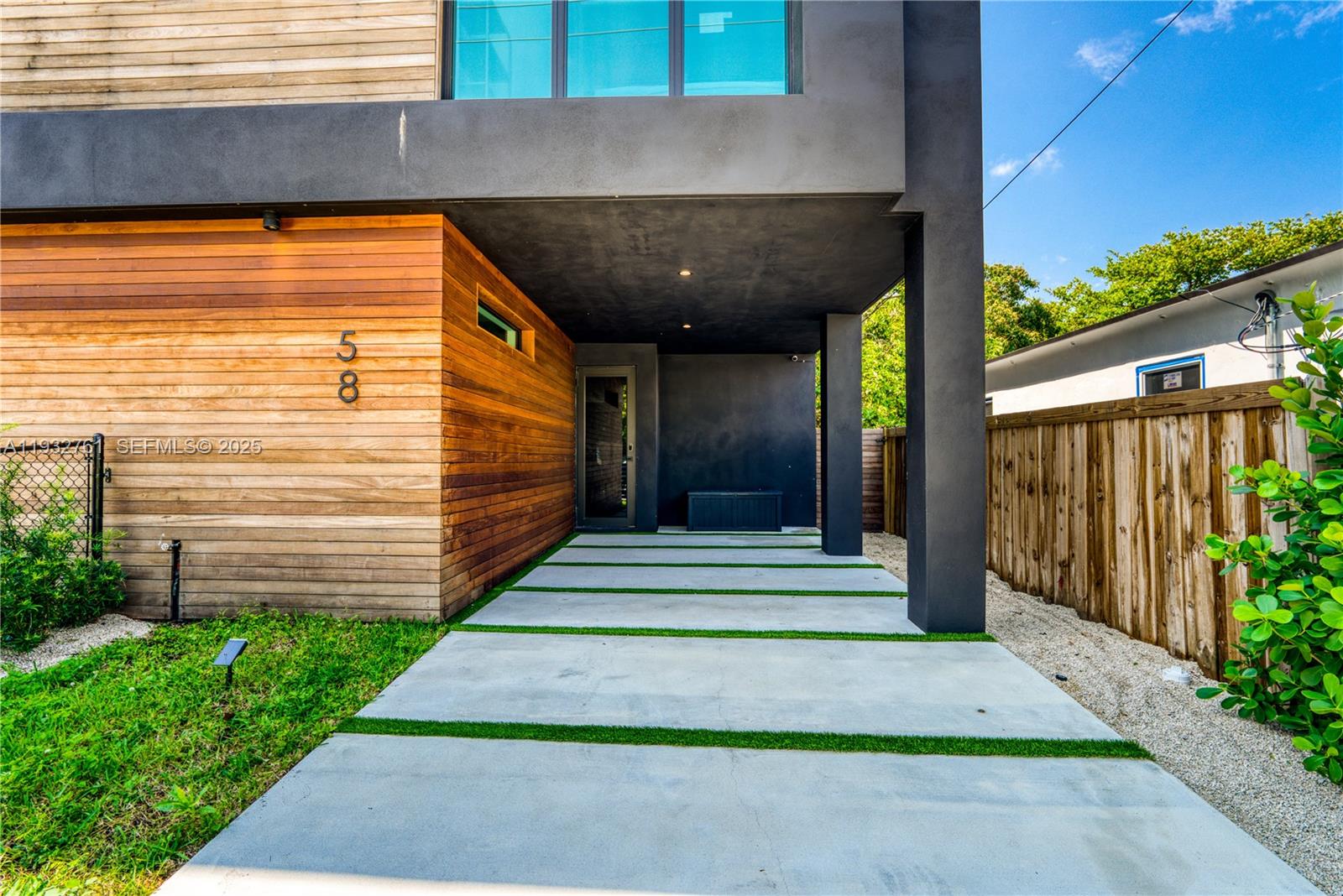 The exterior of a modern home features wood siding, a concrete driveway, and black accents — 58 NW 52nd St, Miami FL 33127, MIAMI, FL