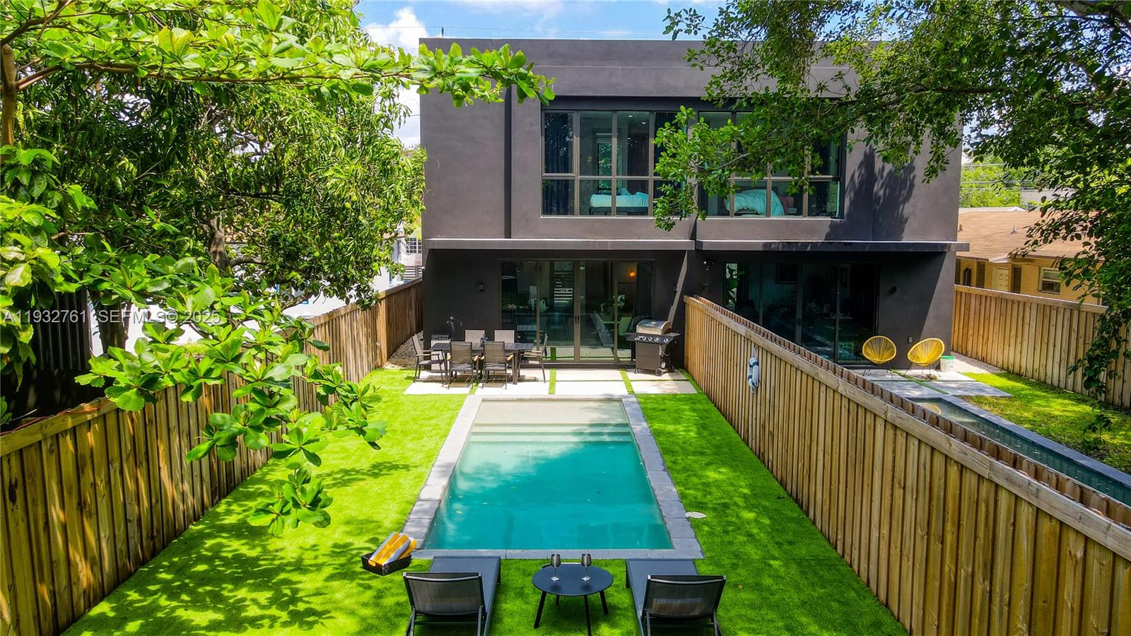 A modern two-story house with a backyard pool, patio furniture, and a wooden fence — 58 NW 52nd St, Miami FL 33127, MIAMI, FL