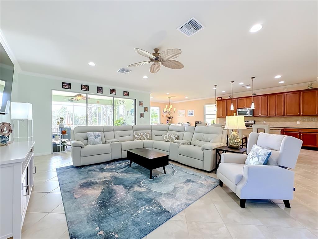 A living room features a large sectional sofa, a blue area rug, and an open kitchen — 6149 ABACO DRIVE, SARASOTA, FL