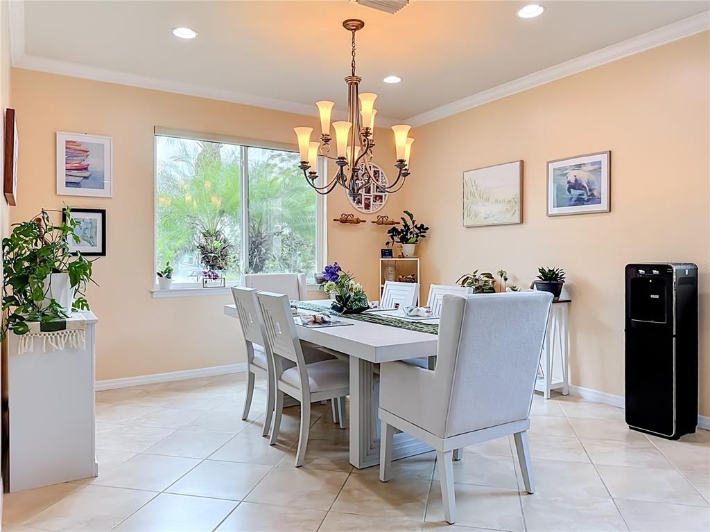 A dining room features a white table, upholstered chairs, a chandelier, and light-colored walls — 6149 ABACO DRIVE, SARASOTA, FL