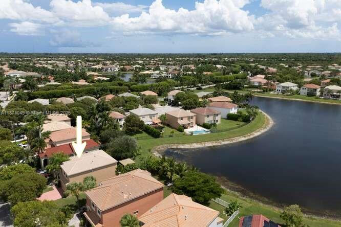 An aerial view shows a suburban neighborhood with houses, a lake, and green landscaping — 9770 Scribner Ln, Wellington FL 33414, WELLINGTON, FL