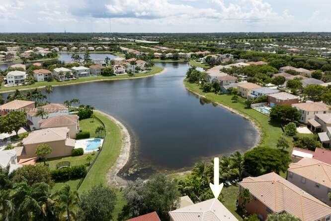 An aerial view shows a residential neighborhood with houses surrounding a central lake — 9770 Scribner Ln, Wellington FL 33414, WELLINGTON, FL