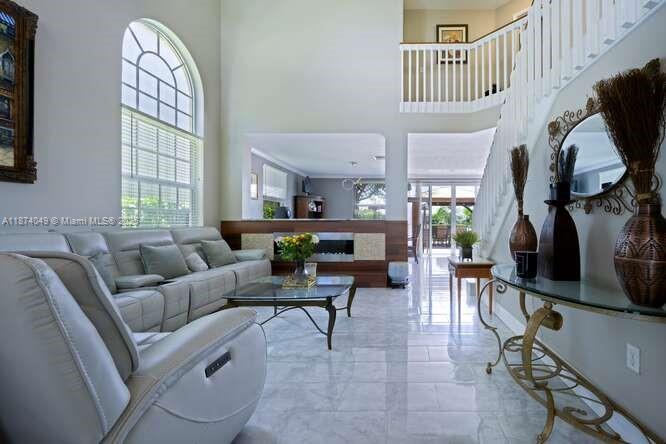 A bright living room features a white leather sofa, marble floors, and a grand staircase — 9770 Scribner Ln, Wellington FL 33414, WELLINGTON, FL